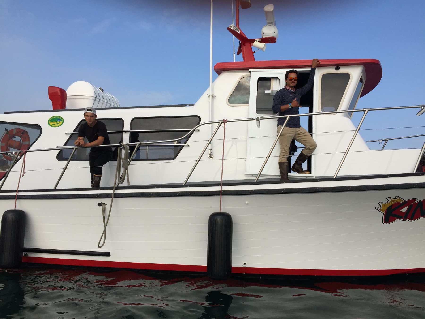 Captain Pono and a first mate stand aboard the King Pin, a white charter boat in Alaska waters.
