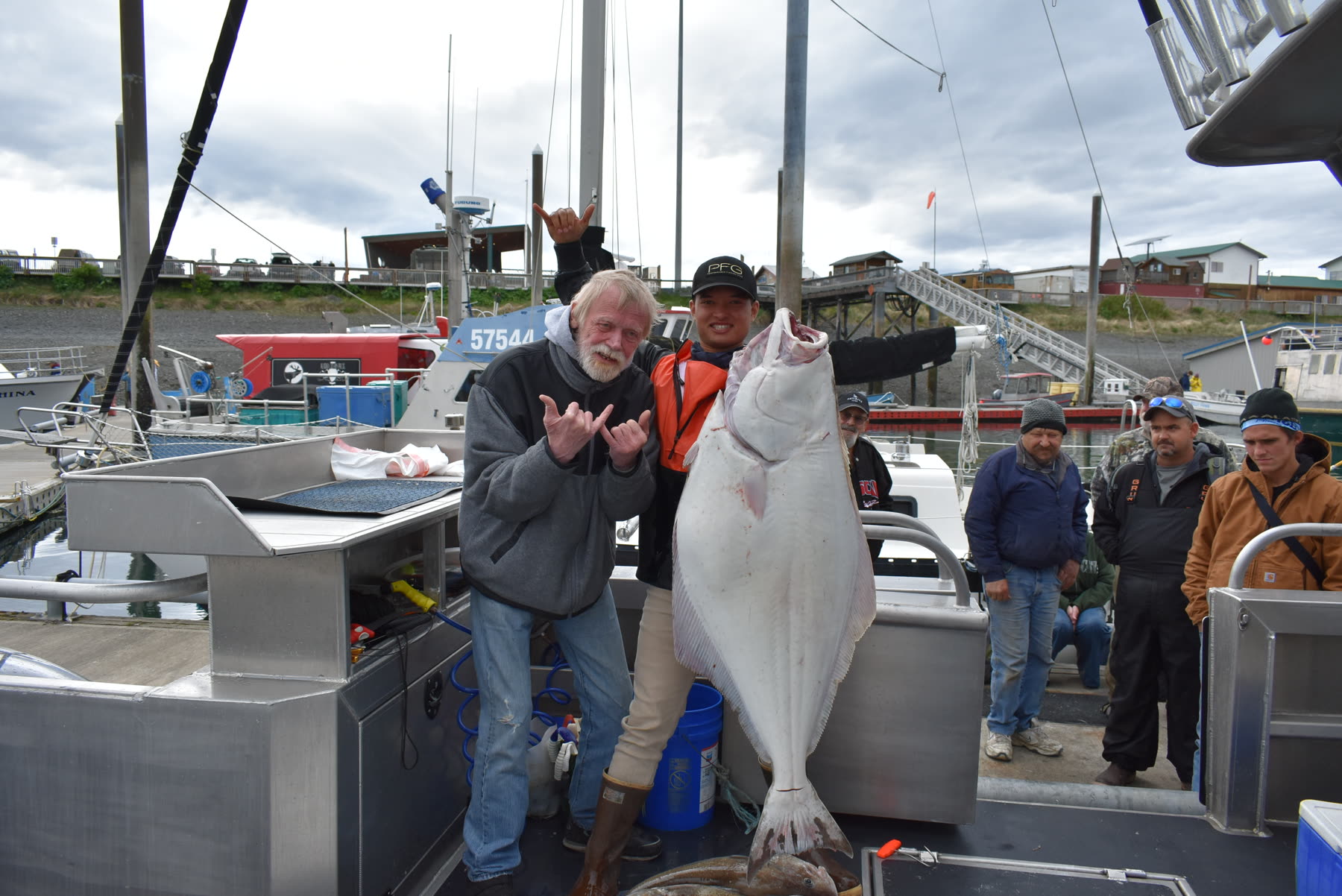Captain Pono and a guest display a large halibut aboard an Alaska fishing boat.